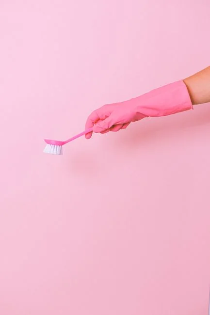 home-services-02 A hand wearing a yellow rubber glove holds a red and white spray bottle against a neutral background.